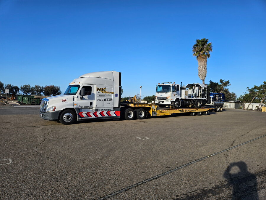 NK Towing tractor hauling a Landoll trailer with heavy equipment